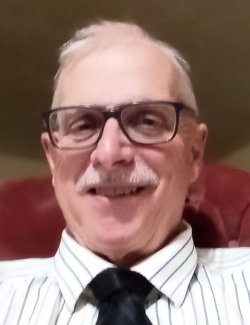 Photo of Henry Skjerven a white male, wearing glasses, white striped shirt and black tie.