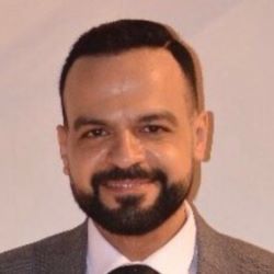 Photo of Eslam Kandeel, a male with dark hair, beard and mustache wearing a brown suit and tie.